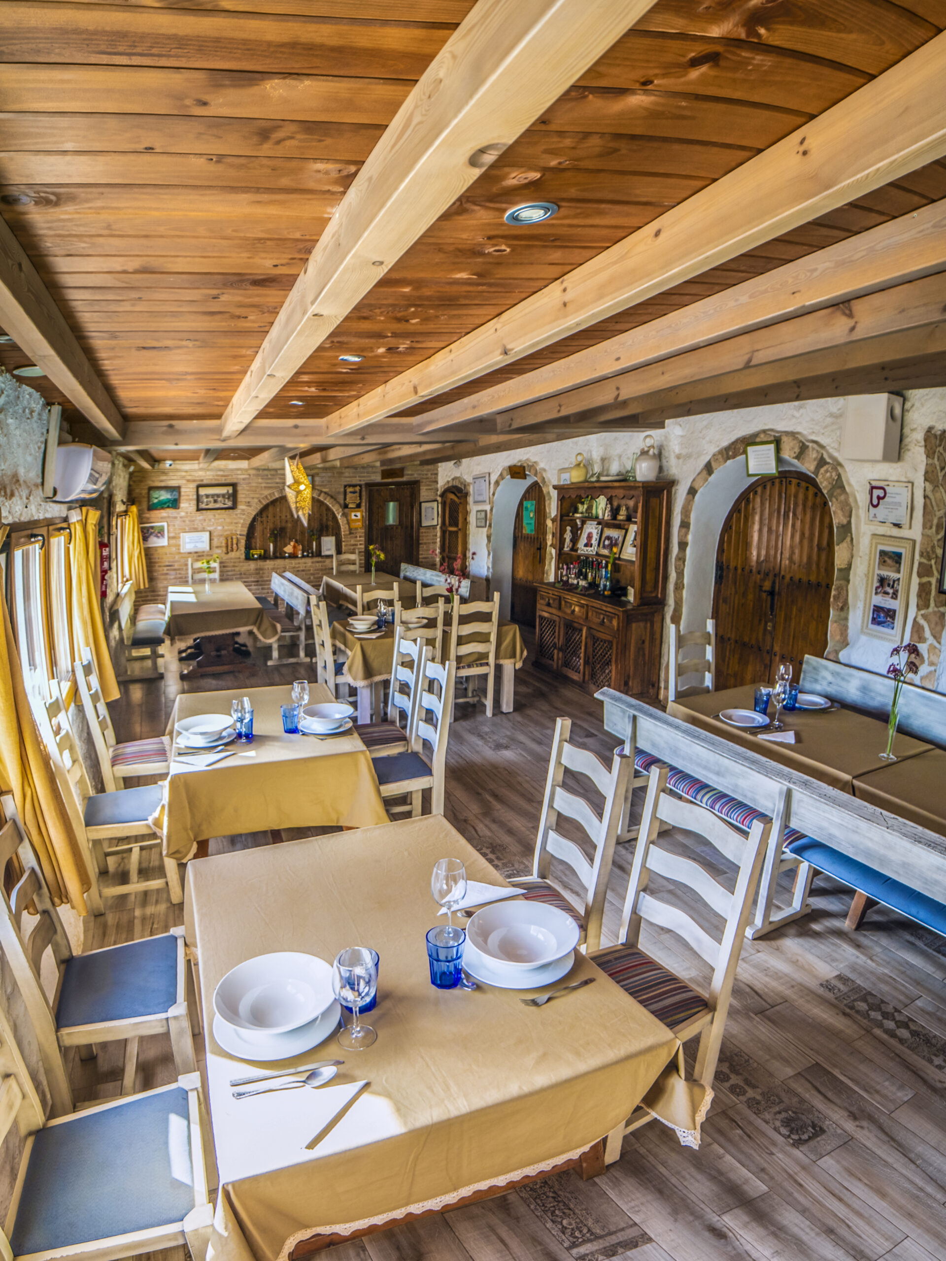 Interior rústico de restaurante con mesas preparadas.