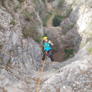 Escaladora rapelando en cañón rocoso.