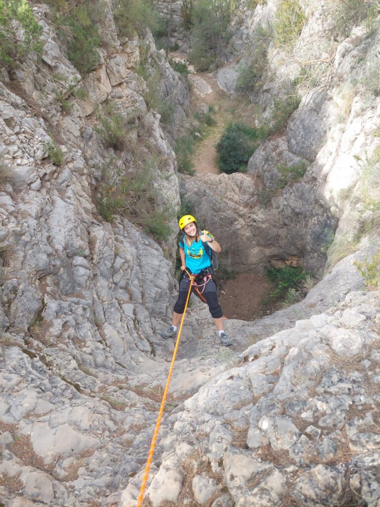 Escaladora rapelando en cañón rocoso.
