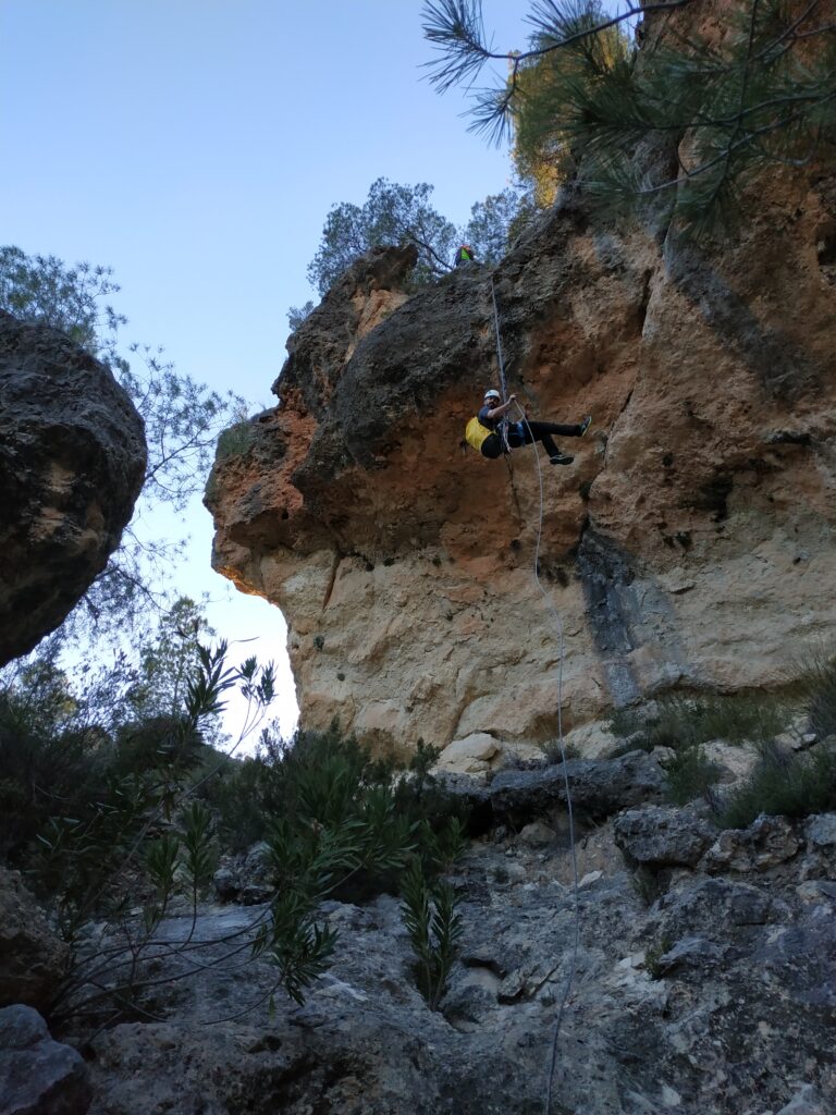 Escalador descendiendo en rápel por acantilado rocoso.