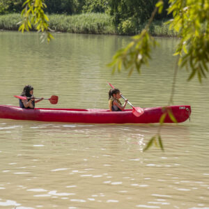 Personas remando en canoa roja en lago.