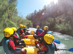 Personas haciendo rafting en un río soleado.