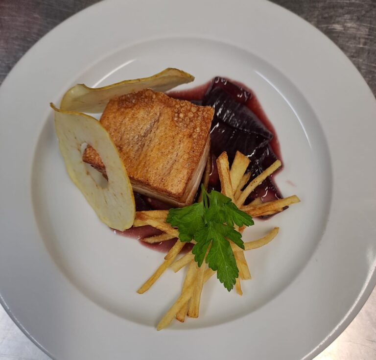 Plato gourmet con pescado, verduras y salsa de remolacha.