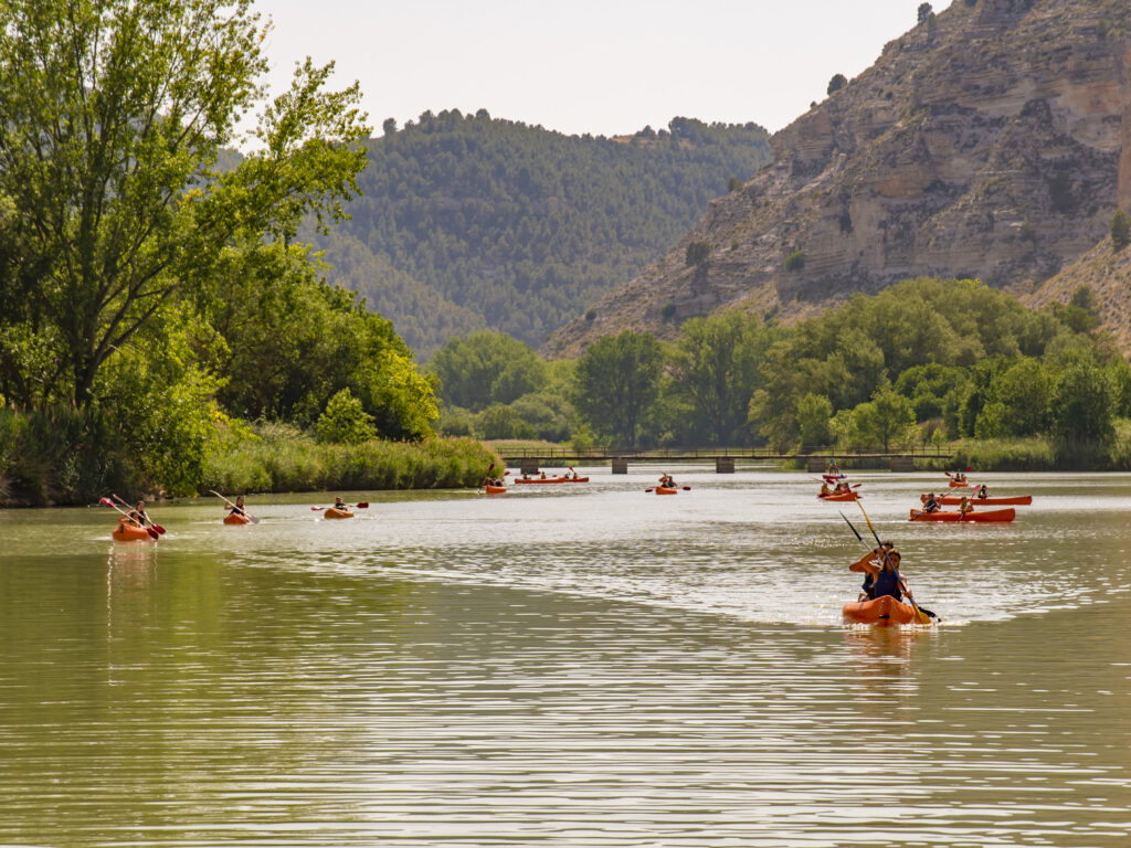 Kayak en río tranquilo con montañas.