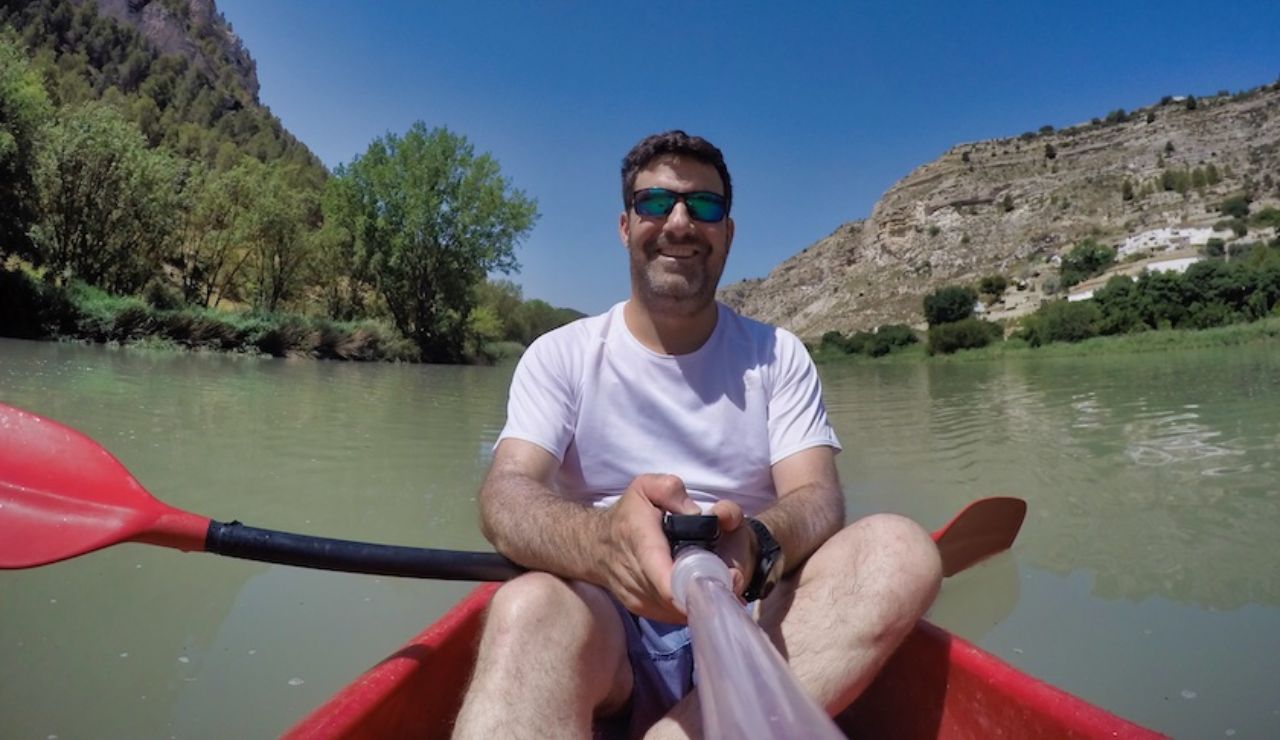 Hombre sonriendo en kayak en río.