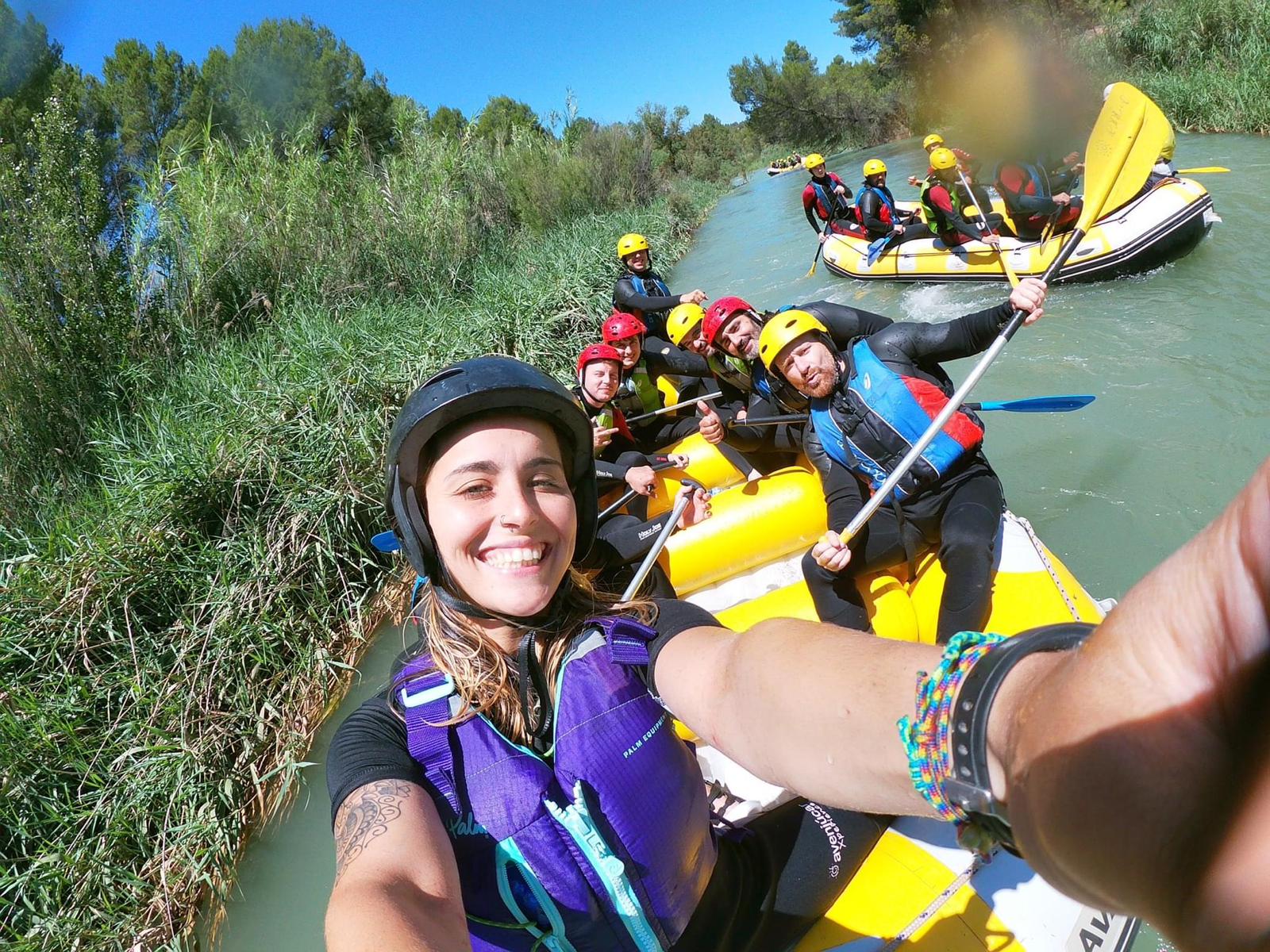 Grupo sonriente haciendo rafting en río.